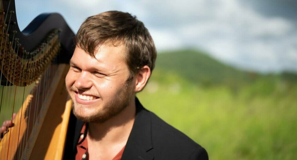 Jonathan up close smiling holding the harp